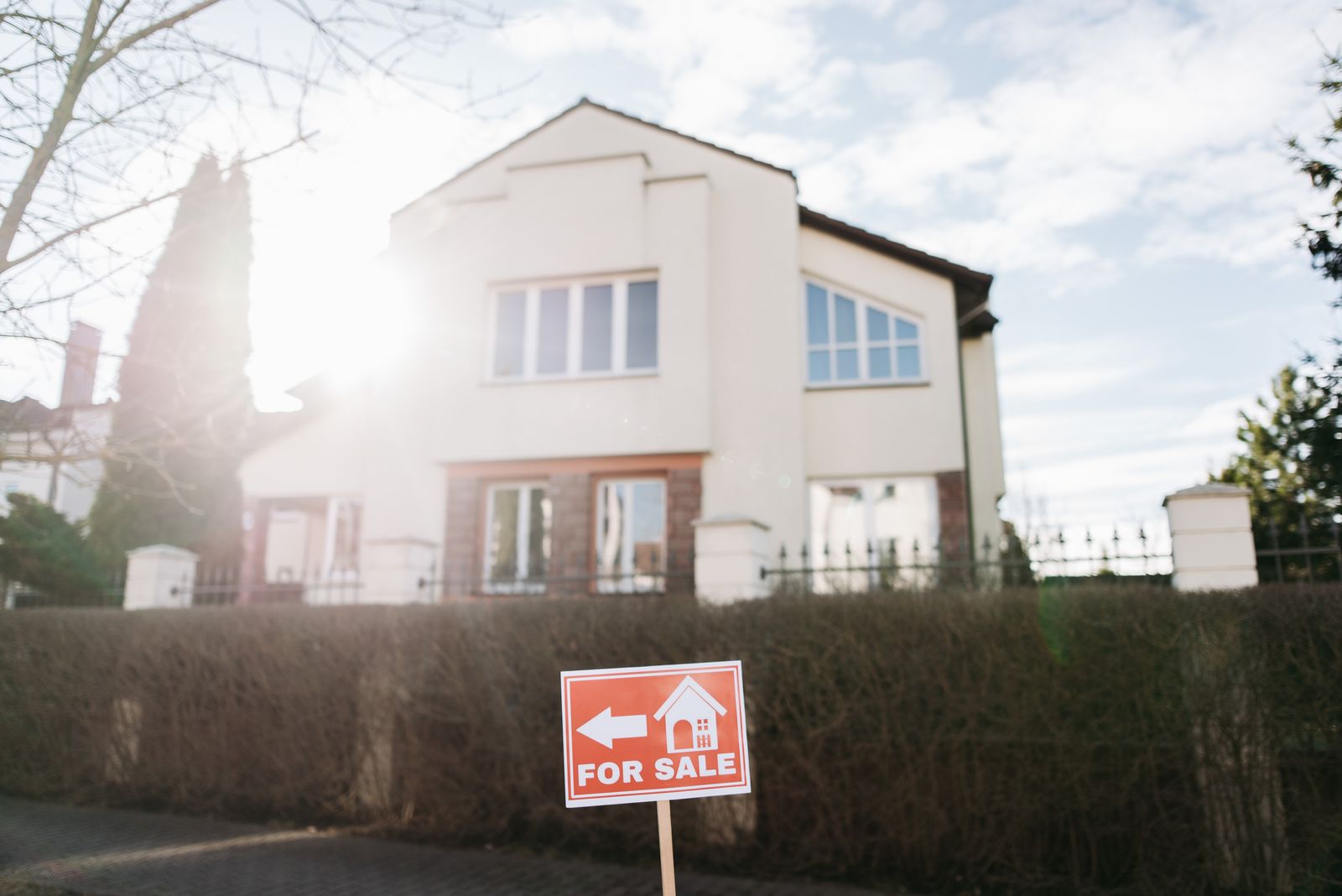 A red 'For Sale' yard sign in front of a residential home, golden-hour light, late-fall trees — the visual question every FSBO listing answers