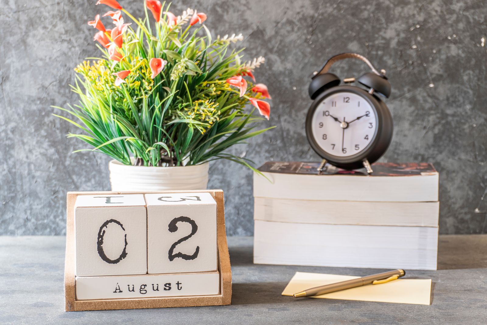 A desk arrangement with a wall calendar, an analog clock, and a stack of books — the scheduling and report-turn timeline that decides when a Utah appraisal lands