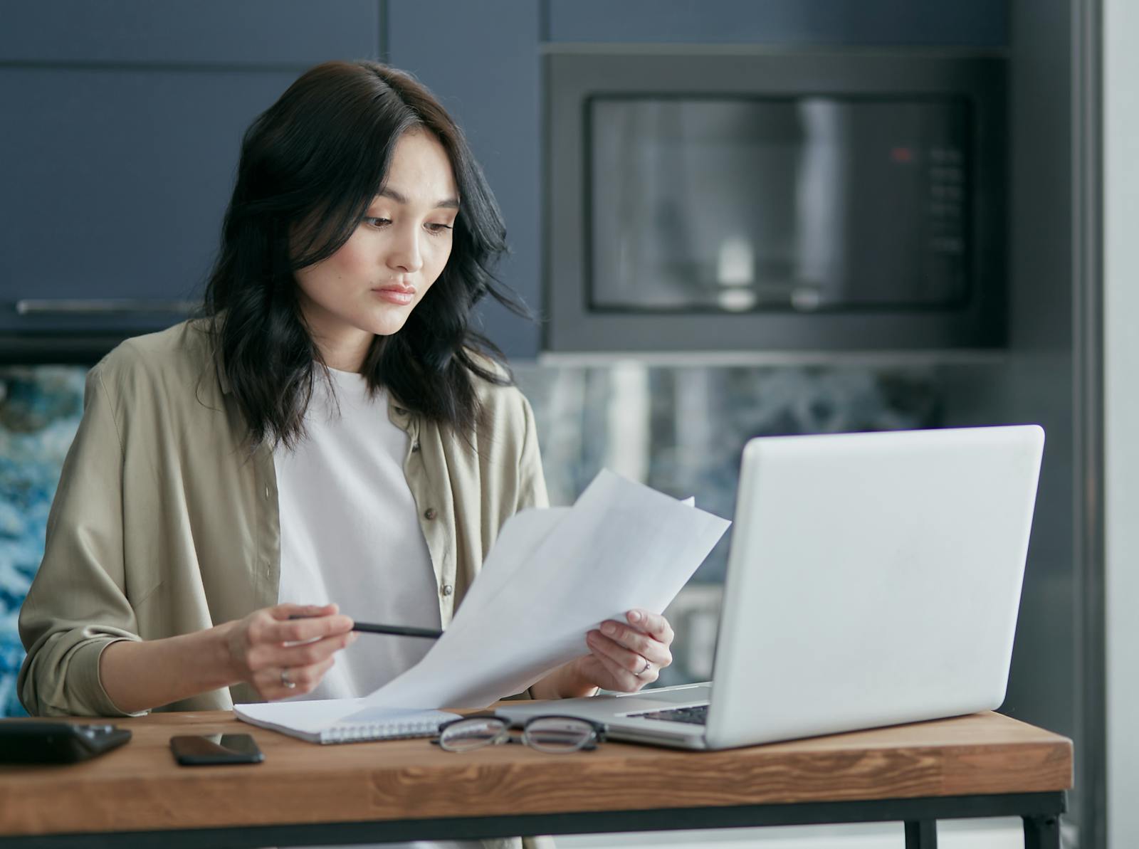 Homeowner reviewing property documents on a laptop at a kitchen table